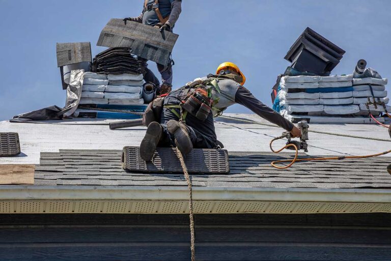 A homeowner on a ladder closely inspecting discolored patches on a clay tile roof.