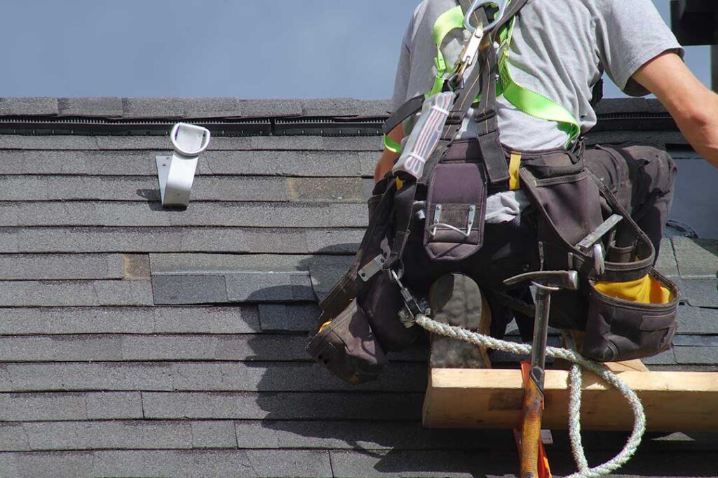 Homeowner checks roof tiles and clear gutters before dark storm clouds arrive.